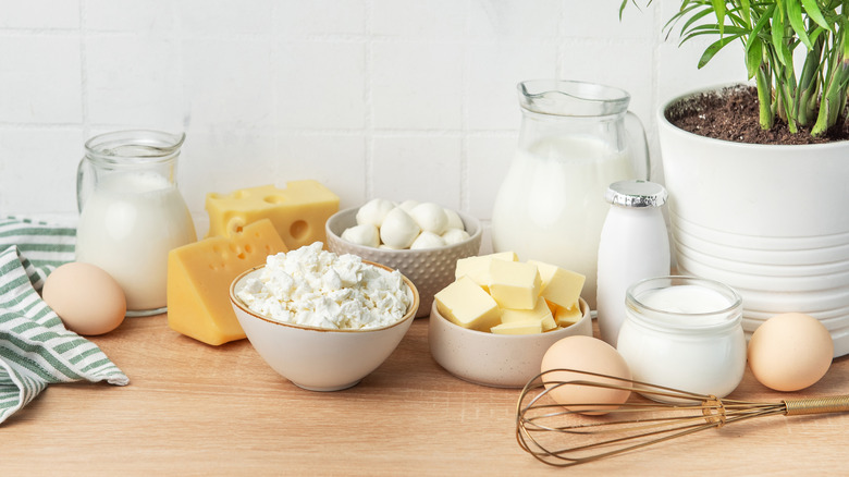 Assorted dairy products on a table with a whisk and a kitchen towel