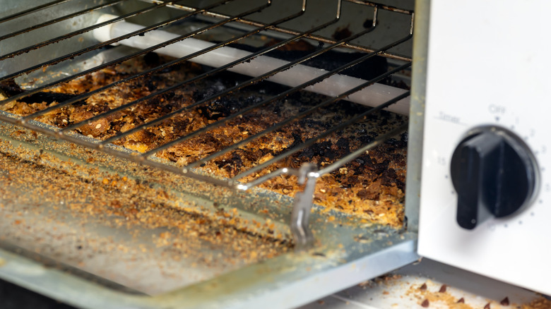 Close-up of crumb-filled tray of a dirty toaster oven