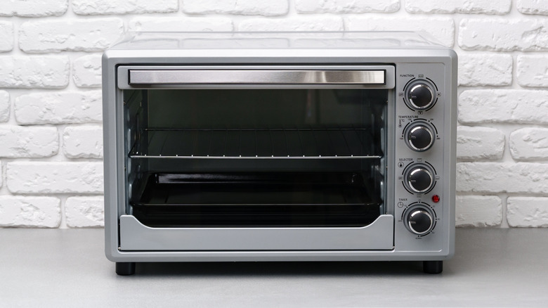 Clean toaster oven on countertop with white brick background