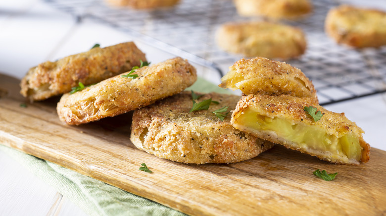 Fried green tomatoes stacked off-center, with one cut open, showing its interior