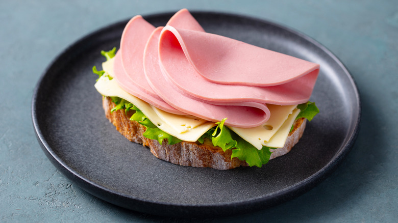 An open-faced bologna sandwich with lettuce and cheese