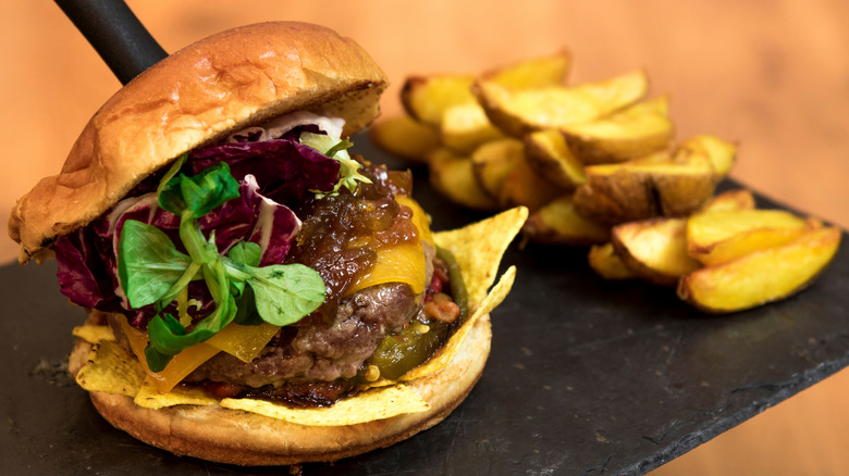 Lentil burger on a bun with potato wedges on the side.