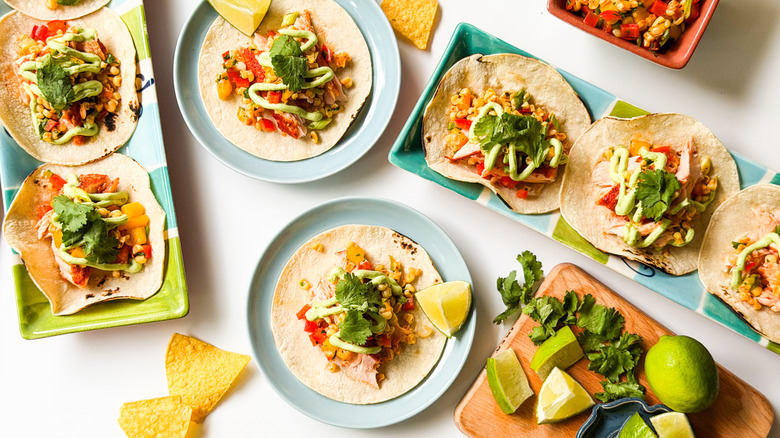 Slow-baked salmon tacos with mango-corn salsa on serving platters and plates
