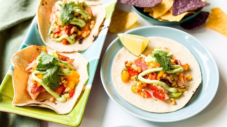 Slow-baked salmon tacos with mango-corn salsa on platter and plate with chips