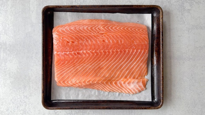 Fresh salmon filet on parchment-lined baking sheet