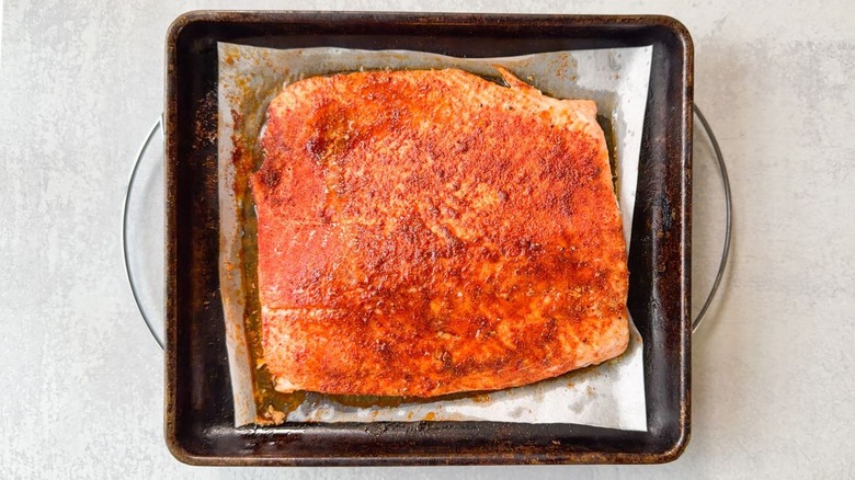 Seasoned and baked salmon filet on parchment-lined baking sheet on cooling rack