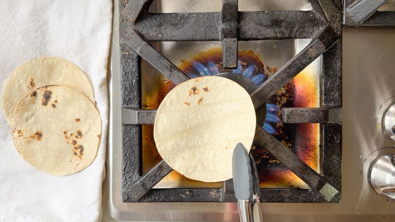 Warming corn tortillas over gas flame on stovetop