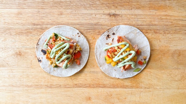 Avocado crema on top of slow-baked salmon tacos with mango-corn salsa
