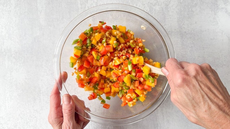 Mixing mango-corn salsa in glass bowl with wooden spoon