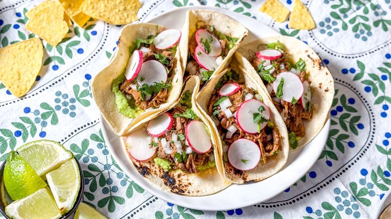 Slow cooker barbacoa tacos on serving platter with limes and tortilla chips