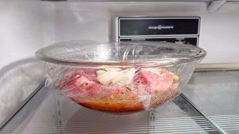 Beef chuck marinating in barbacoa marinade in glass bowl in refrigerator