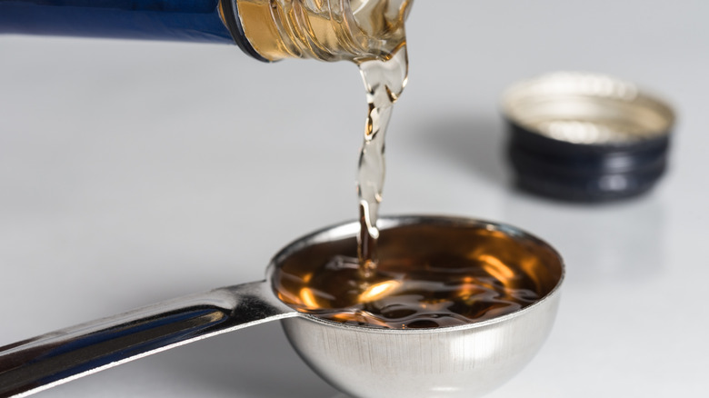 Pouring cooking sherry into measuring spoon.