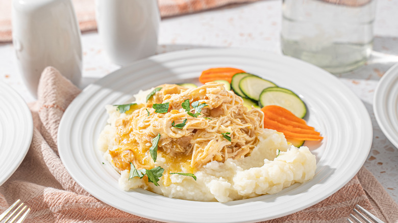 bowl of chicken and gravy on mashed potato with vegetables