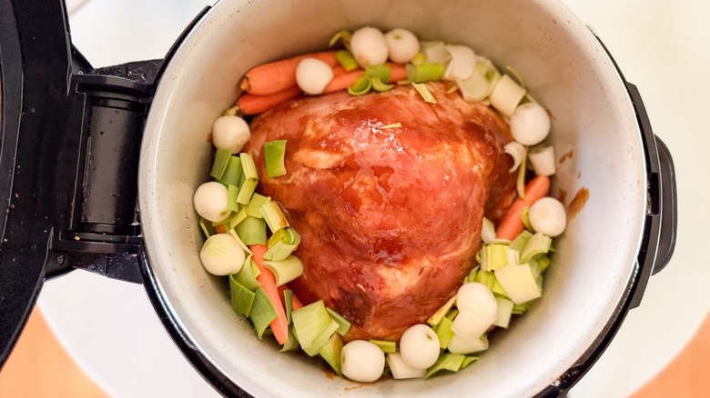 Raw baby vegetables in slow cooker with glazed ham