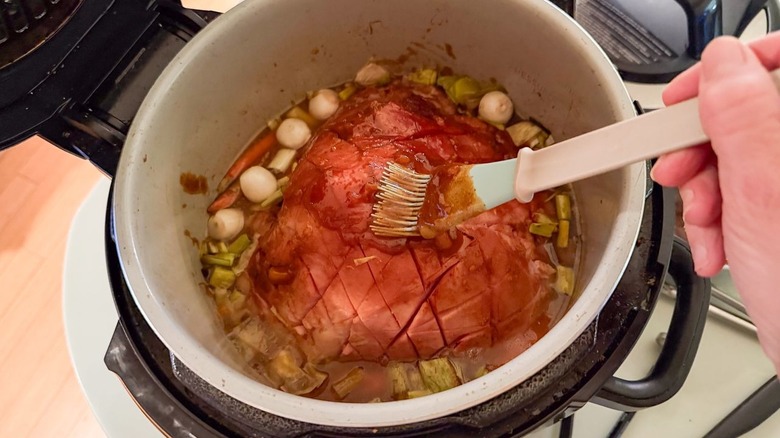 Brushing Kahlua apricot glaze on ham in slow cooker