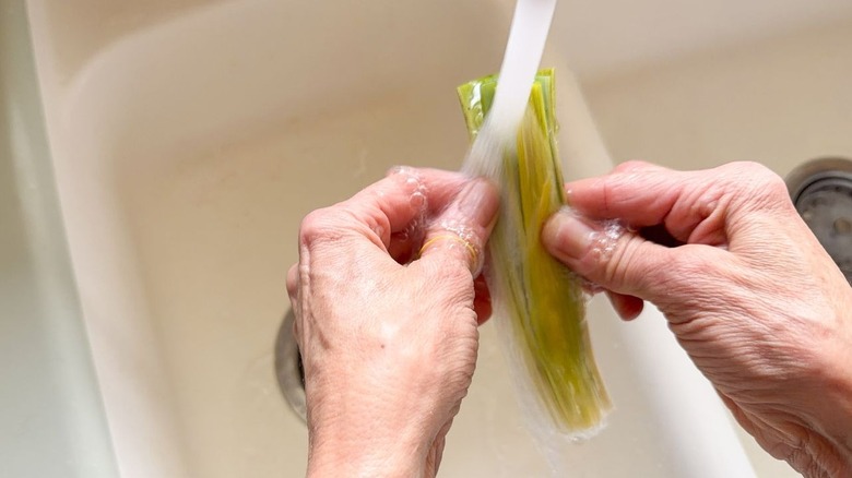 Rinsing leeks under running water in sink
