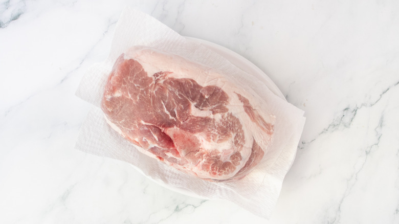 Raw pork butt on a large plate with paper towels