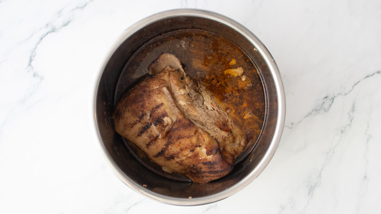 Cooked pork butt in a large slow cooker pot