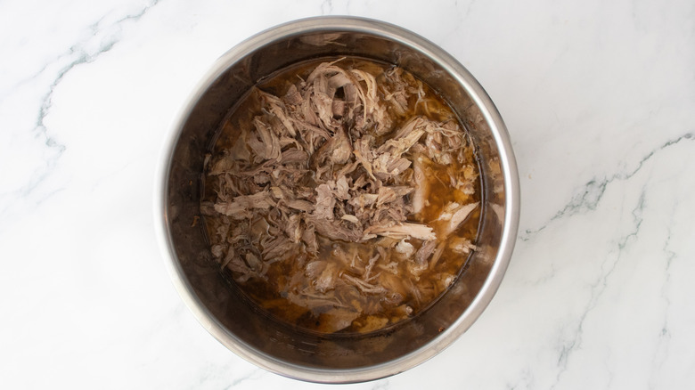 Pulled pork and pan drippings in a large slow cooker pot