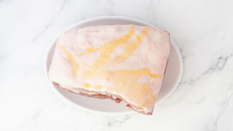 Raw pork butt on a large plate drizzled with olive oil