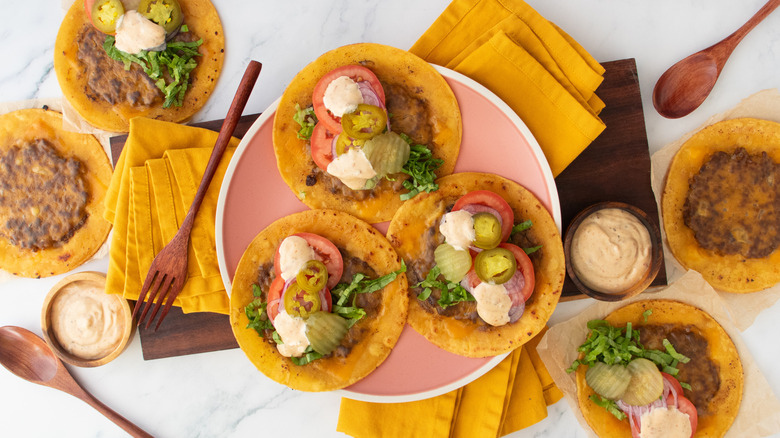 Overhead shot of several smash burger tacos with condiments and toppings