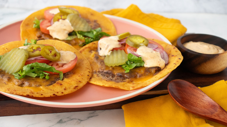 A side shot of a plate of smash burger tacos