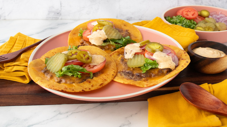 A side shot of a plate of smash burger tacos