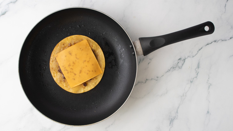 Melted slice of cheese on a burger patty-filled tortilla