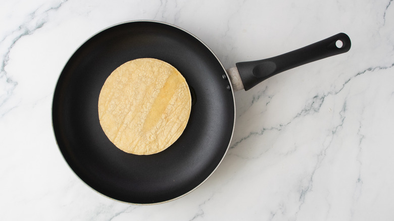 A corn tortilla in a nonstick skillet