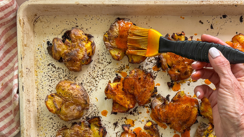 hand brushing sauce on potatoes