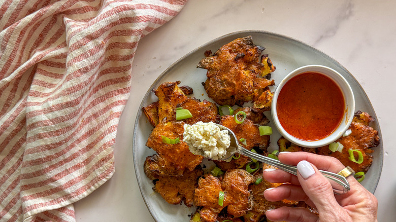 hand adding blue cheese to potatoes