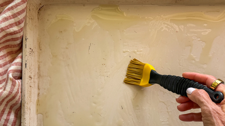 hand brushing oil on sheet pan