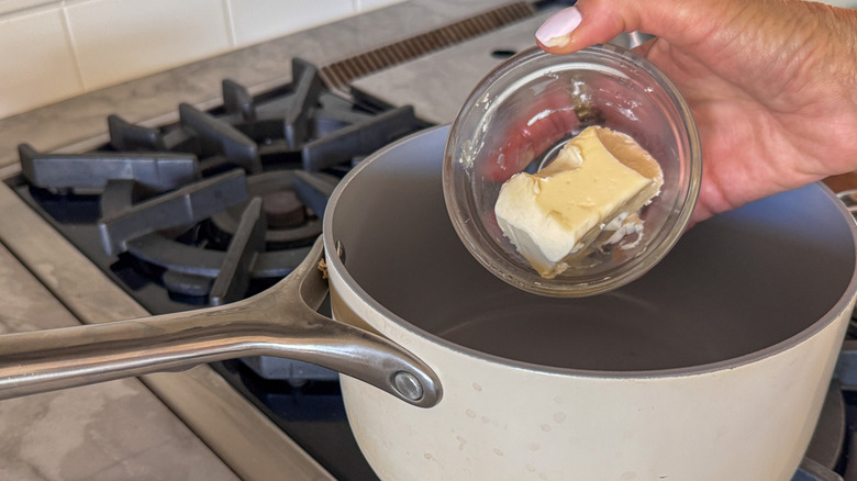hand adding butter to pot
