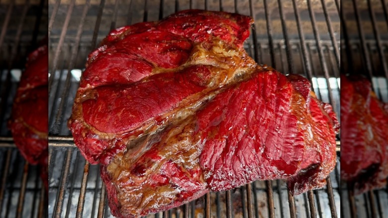 Chuck roast being cooked on open grill for pot roast.