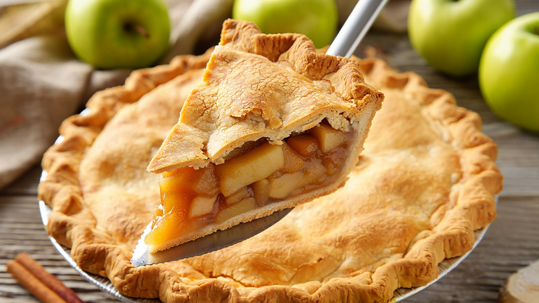 A slice of fresh homemade apple pie is lifted fom a tin