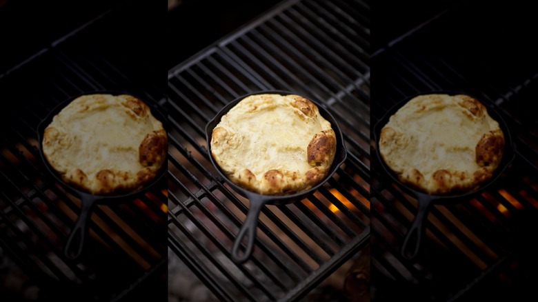 A person is seen cooking at a backyard grill.