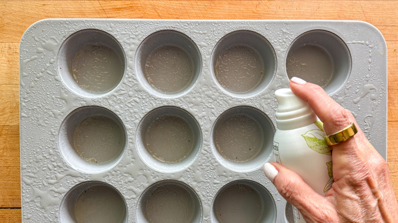 hand spraying muffin tin