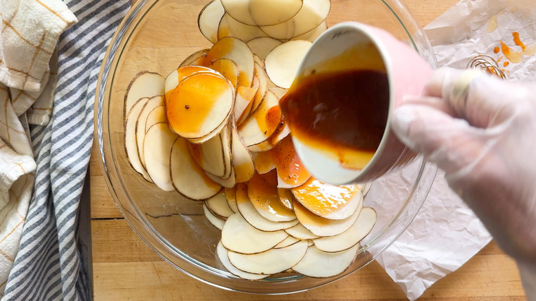 hand pouring sauce over potatoes