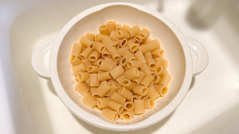 Mezzi rigatoni draining in colander in sink 