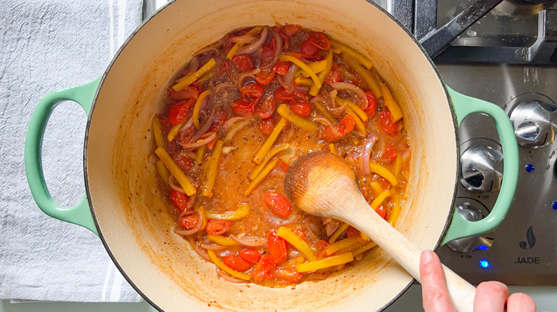 Stirring white wine and mustard into vegetables in pot on stove top with wooden spoon