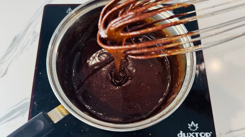 Chocolate mixture in saucepan with whisk above it