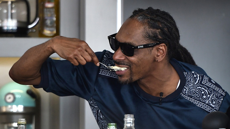 Snoop Dogg tasting one of his own dishes during a cooking demonstration