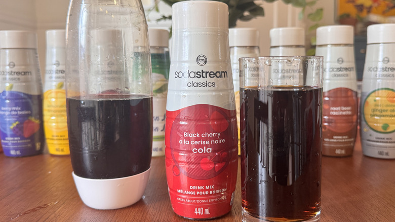 A SodaStream bottle, a syrup bottle and an orange soda glass