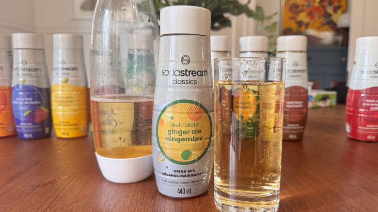 A SodaStream bottle, a syrup bottle and an orange soda glass