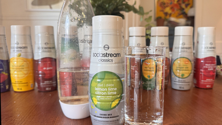 A SodaStream bottle, a syrup bottle and a clear soda glass