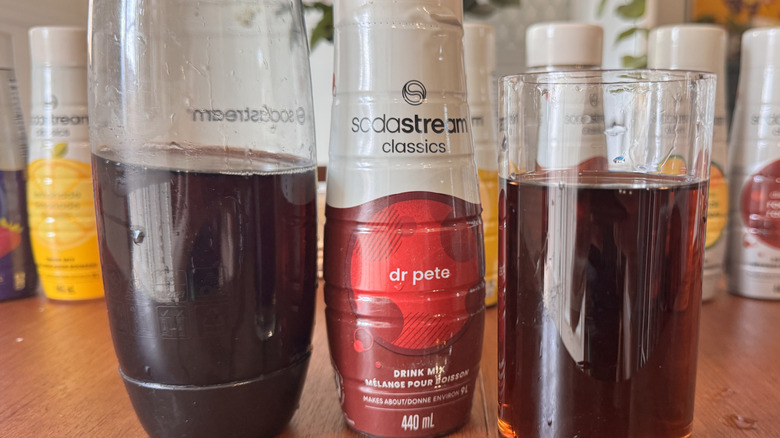 A SodaStream bottle, a syrup bottle and a brown soda glass