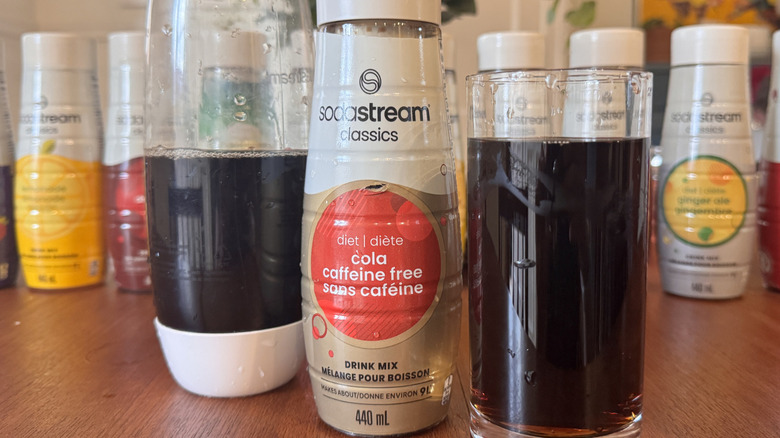 A SodaStream bottle, a syrup bottle and a Cola soda glass