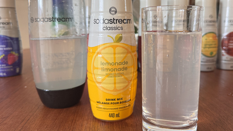 A SodaStream bottle, a syrup bottle and a lemon soda glass