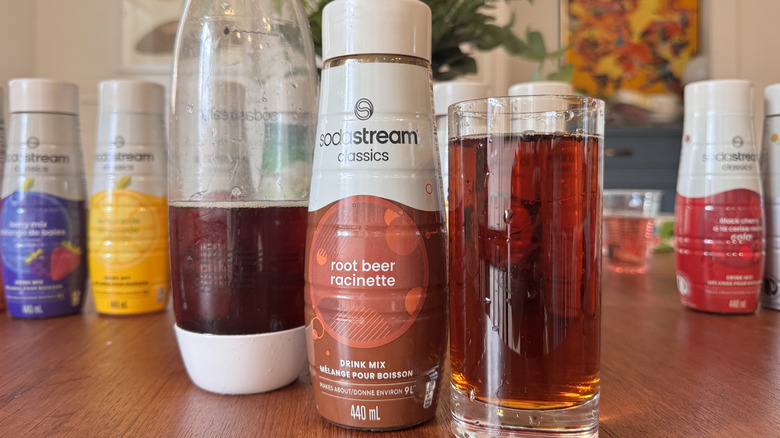 A SodaStream bottle, a syrup bottle and a root beer soda glass