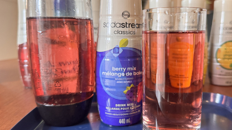 A SodaStream bottle, a syrup bottle and a pink soda glass